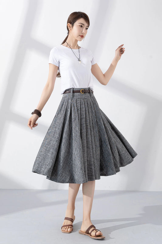 May include: A gray linen skirt with a brown belt and a gold buckle. The skirt is pleated and has a flared silhouette. The skirt is knee-length.
