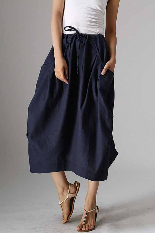 Person wearing navy blue pants and white top on a gray background