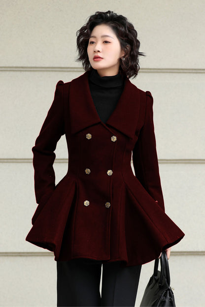 Woman wearing a dark red peacoat with gold buttons against a light background