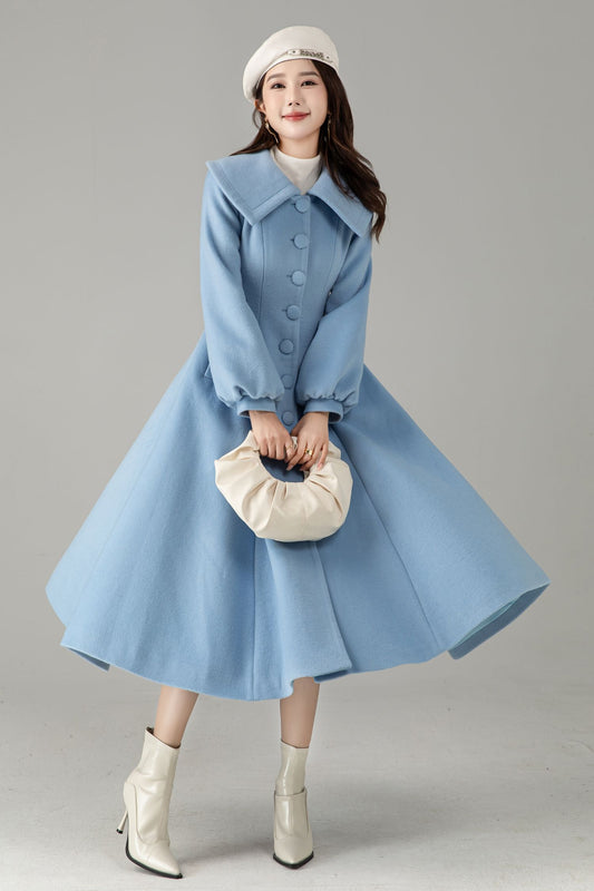 Woman wearing a light blue coat with a skirt, white boots, and a beige bag on a gray background