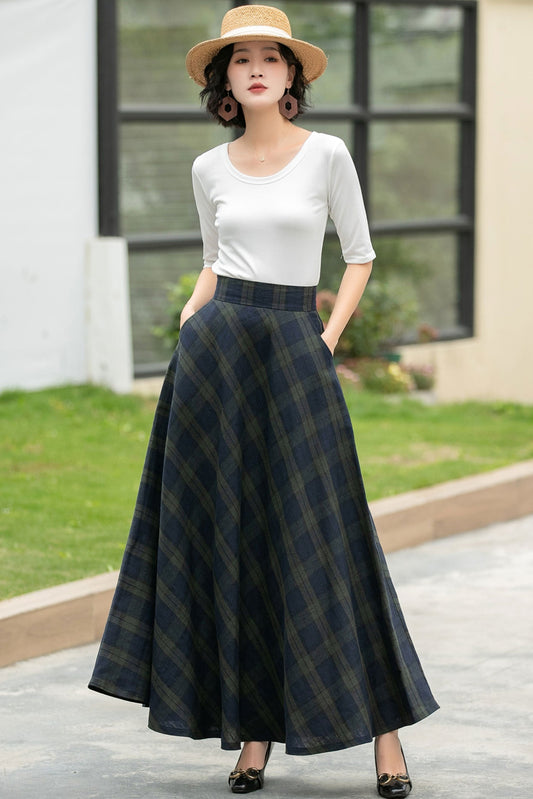 Woman wearing a white top and plaid skirt standing outdoors.