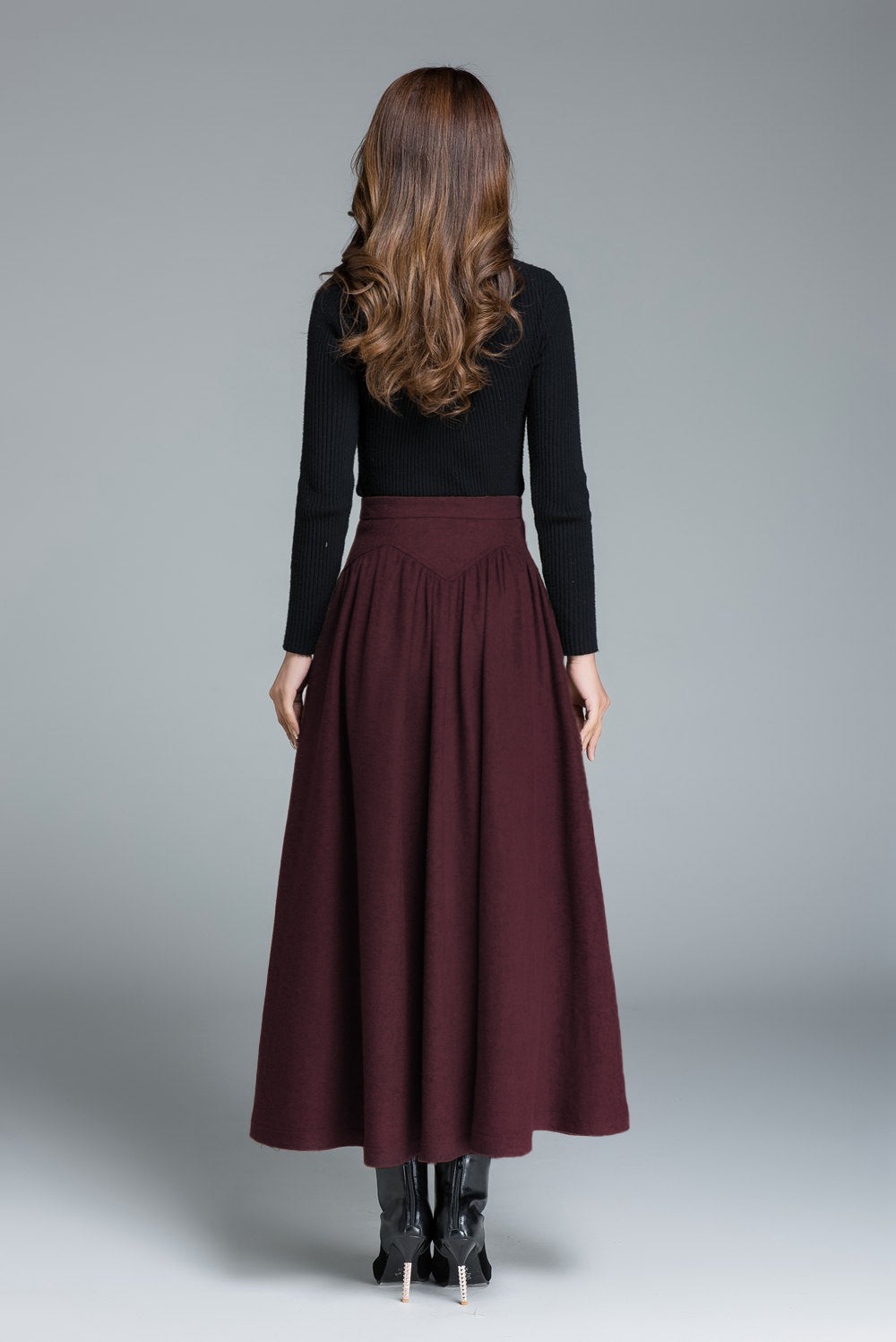 Woman wearing a black top and burgundy skirt on a gray background