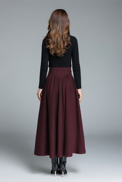 Woman wearing a black top and burgundy skirt on a gray background