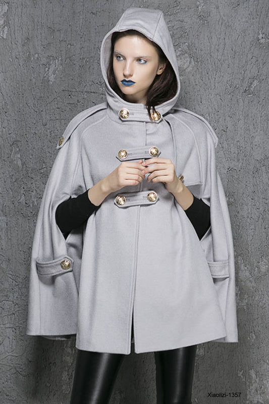 Person wearing a gray hooded coat with gold buttons against a gray background