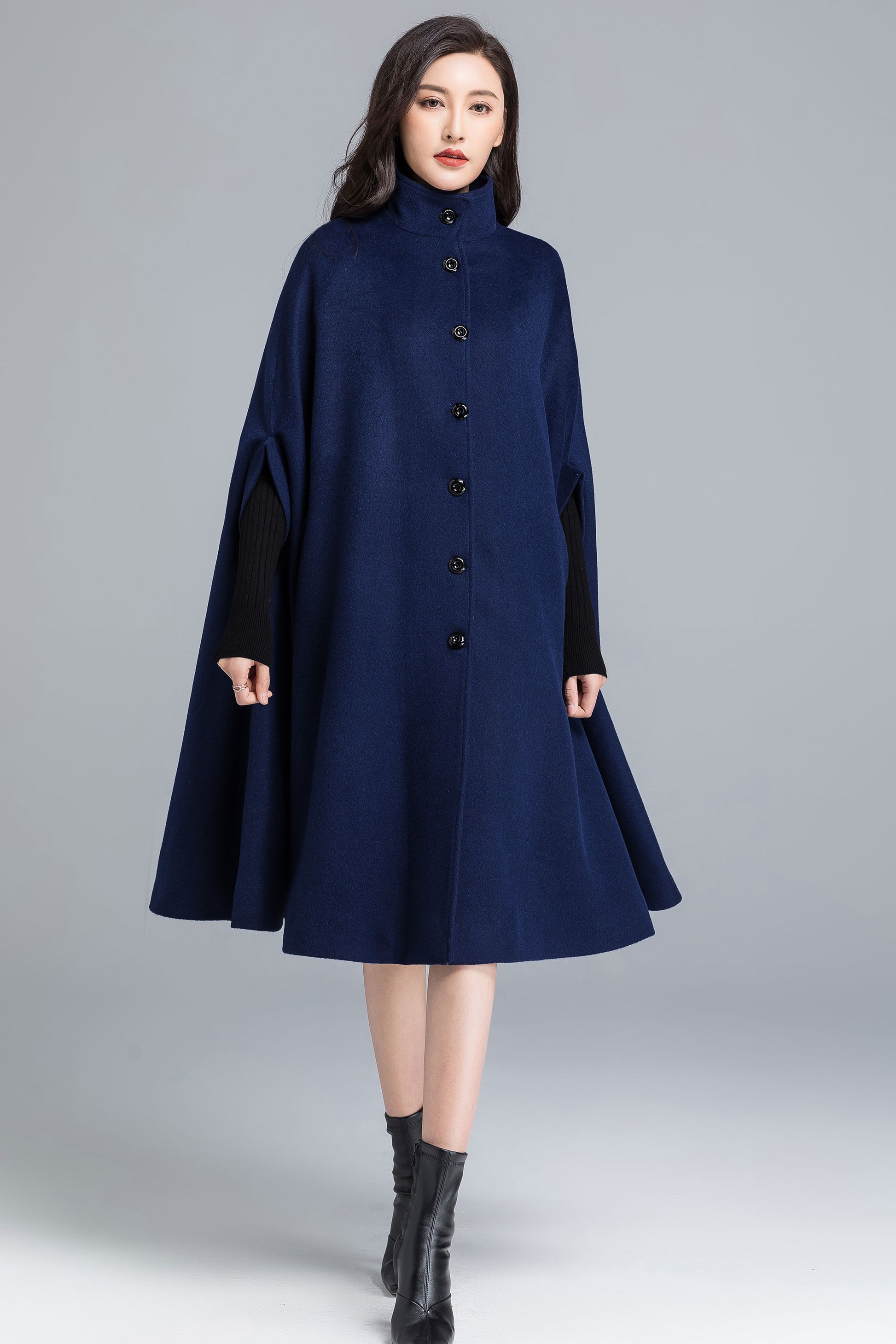 Woman wearing a navy blue coat with black sleeves on a gray background