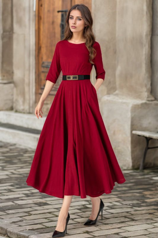 Woman in a red dress standing in front of a stone building.