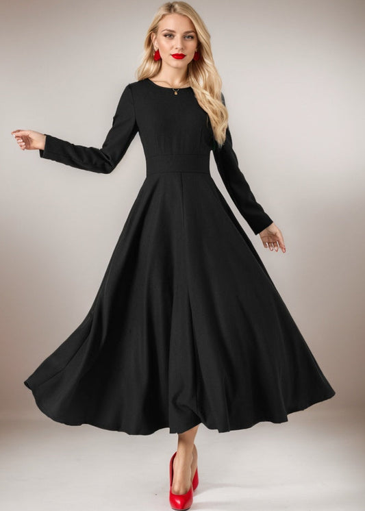 Woman wearing a black dress with long sleeves on a plain background