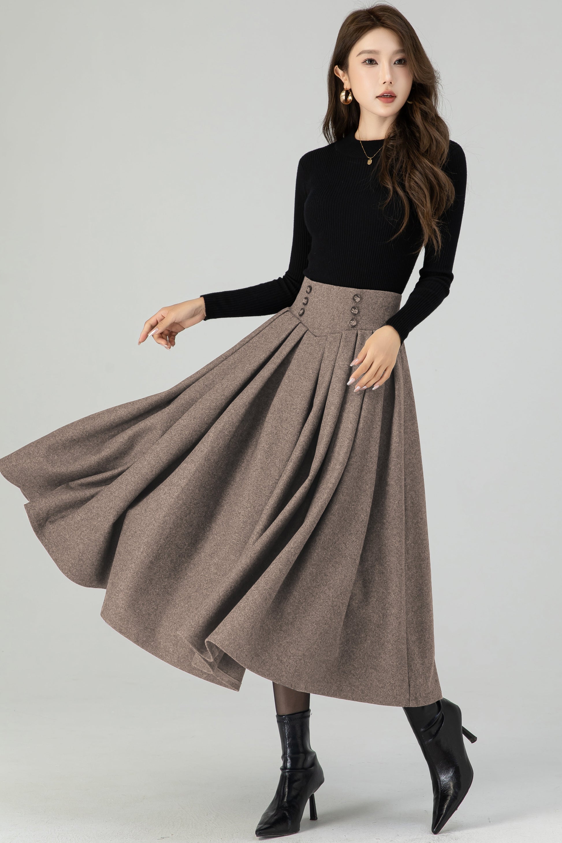 Woman wearing a black top and brown skirt on a white background