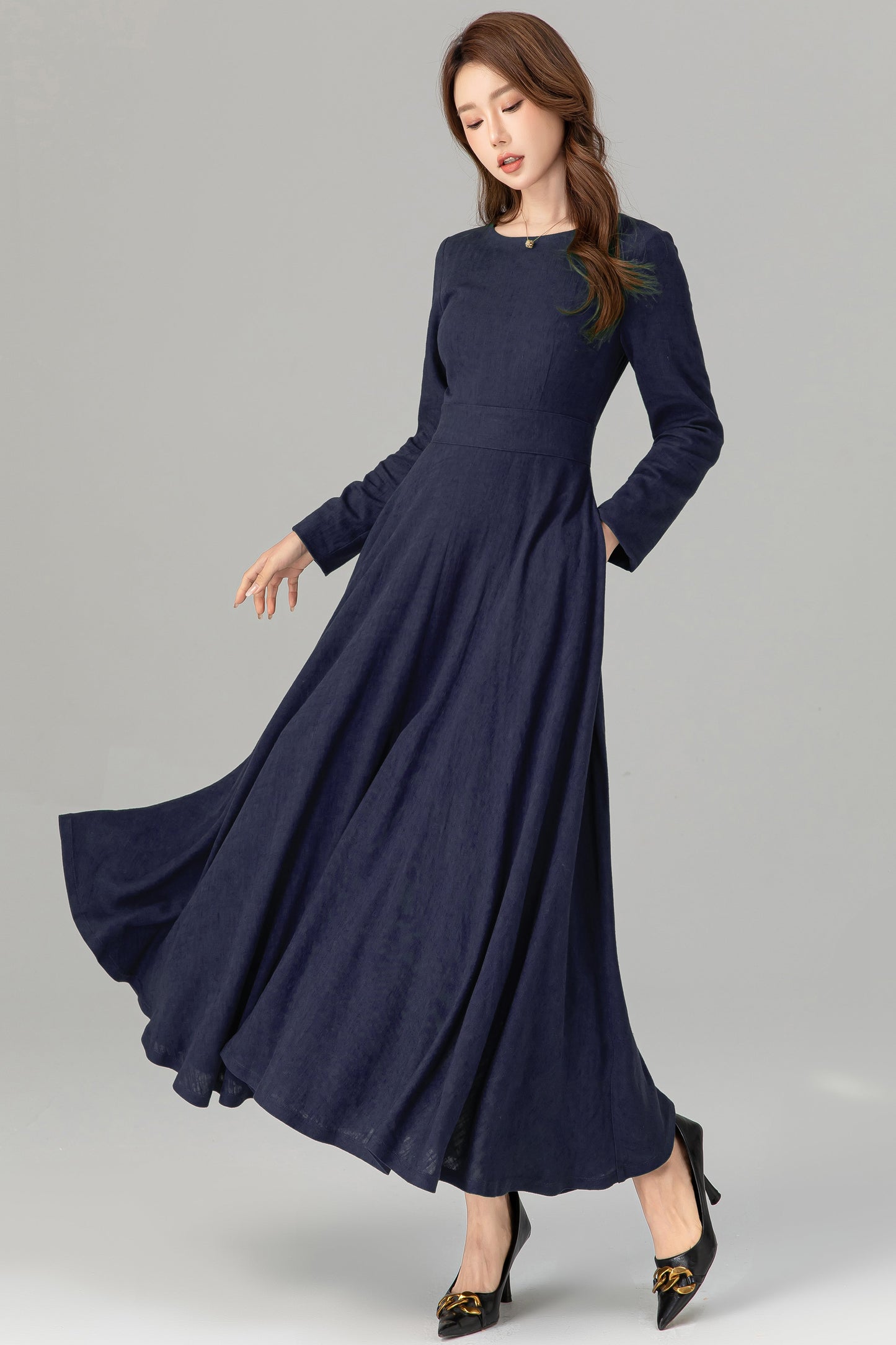Woman wearing a long navy blue dress on a gray background