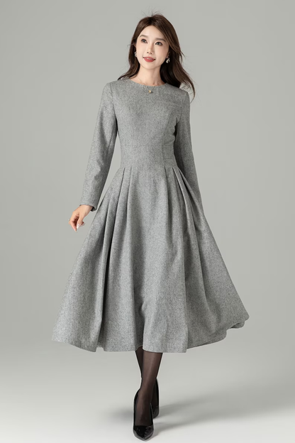 A model wearing a long gray swing wool dress with a round neckline and sleeves, standing against a plain background.