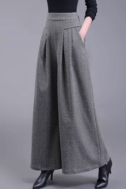 A model wearing wide leg gray wool pants with an elastic waistband and side pockets.