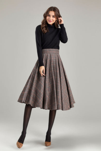A woman wearing a black sweater and a pleated tartan A-line skirt with side pockets and a back zipper closure.