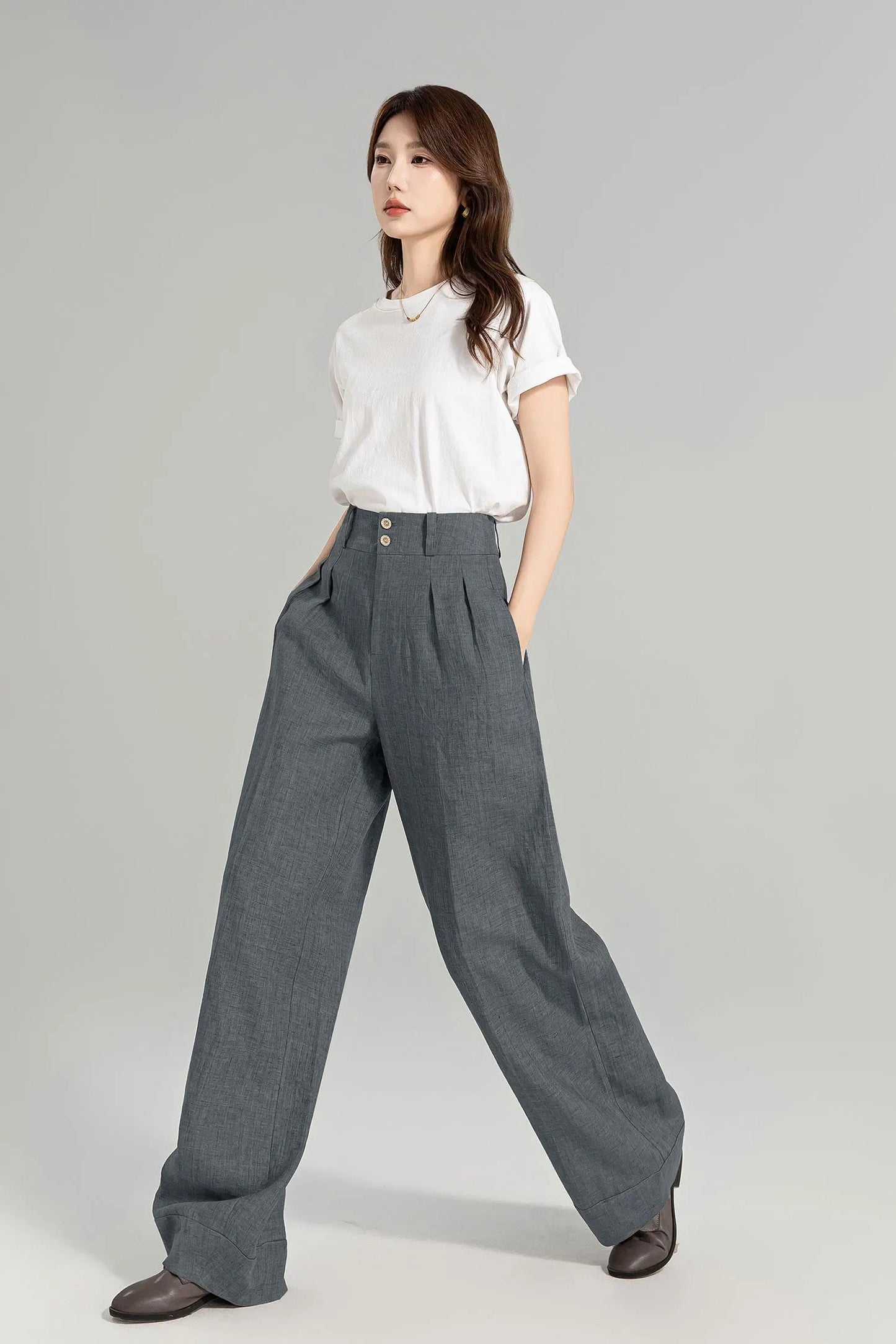 May include: Gray wide-leg pants with a high waist and pleats. The pants have a button closure and are made of a textured fabric.