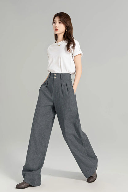 May include: Gray wide-leg pants with a high waist and pleats. The pants have a button closure and are made of a textured fabric.