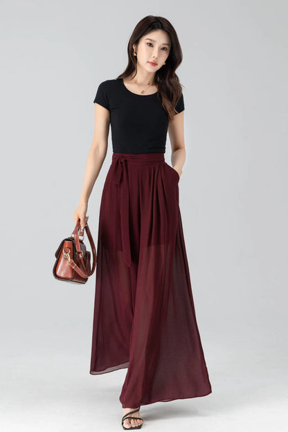 May include: A black short-sleeve top paired with a burgundy wide-leg skirt. The skirt features a high waist with a tie and pockets. A brown leather handbag with a shoulder strap is also visible.