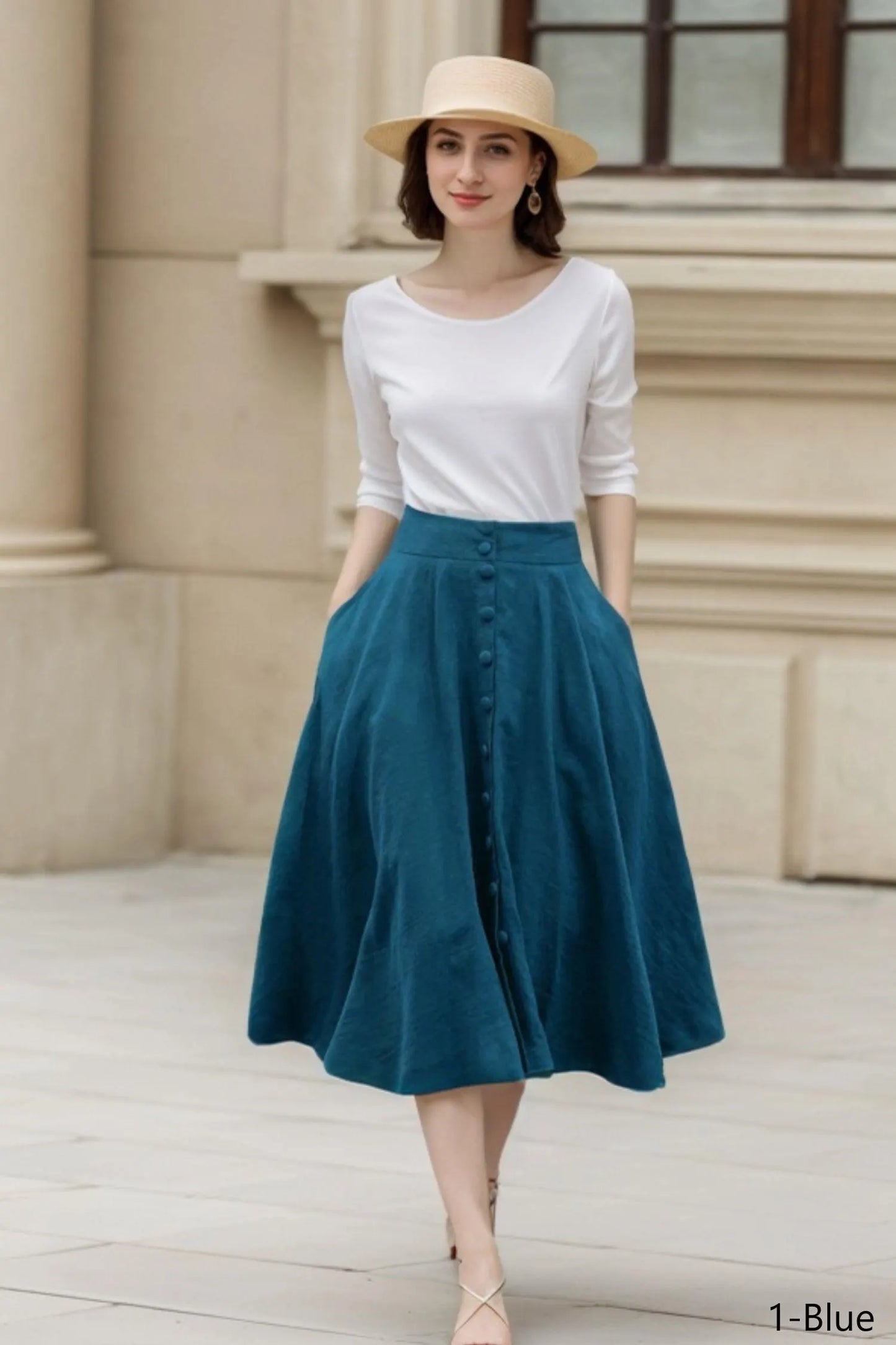 May include: A woman wearing a white long-sleeve top and a teal button-down skirt. She is also wearing a straw hat. The skirt has pockets and buttons down the front. The outfit is suitable for a casual or semi-formal occasion.