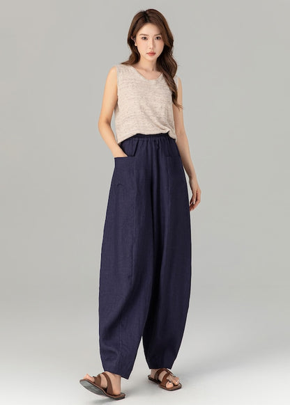 Woman wearing a sleeveless top and navy wide-leg pants on a gray background