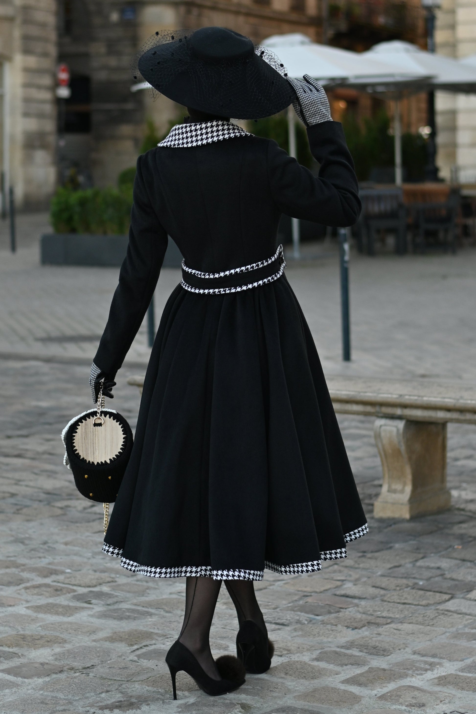 Person wearing a black dress with white patterns on a street.