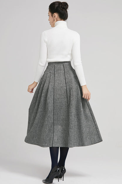 Woman wearing a gray skirt and white turtleneck on a light gray background