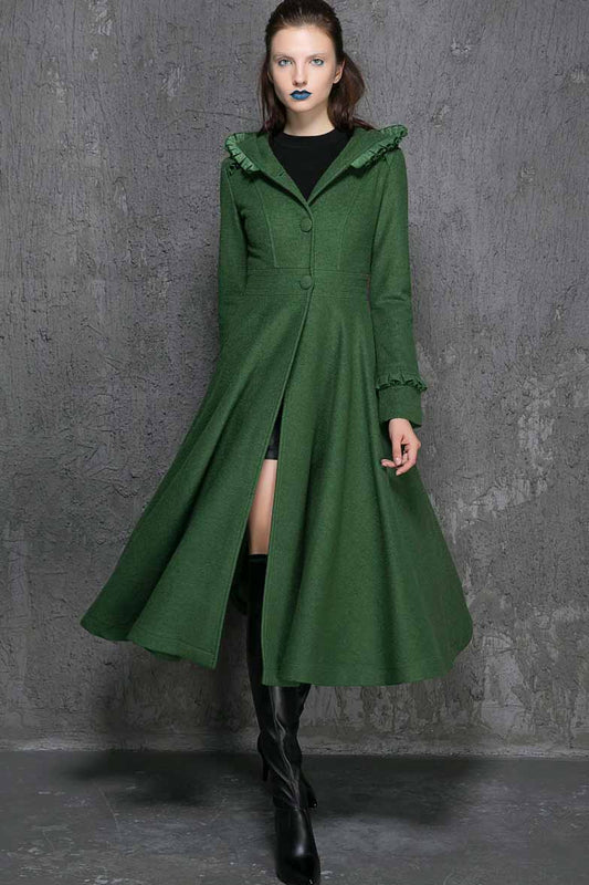 A woman wearing a green, long, hooded coat with ruffle detail and black boots.