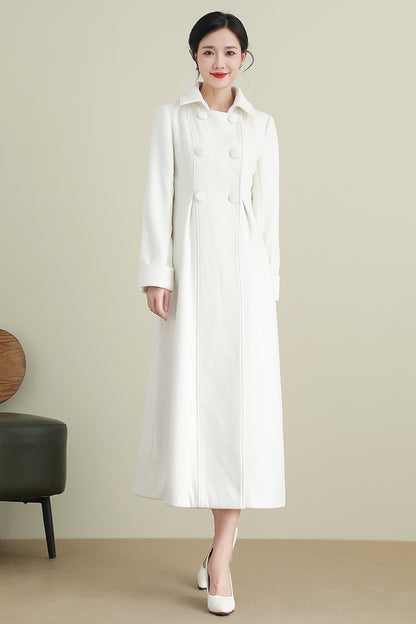 A woman standing wearing a white long sleeve wool coat with double breasted button closure and two side seam pockets.