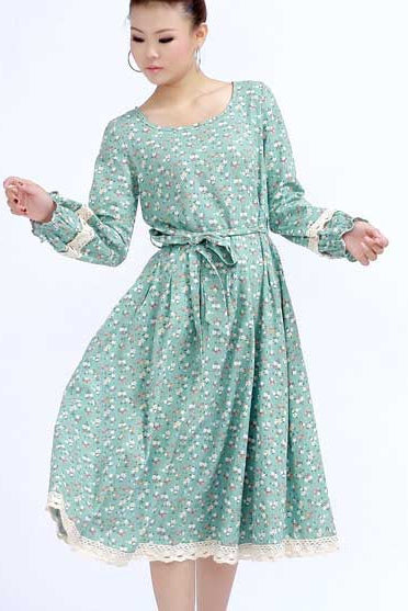 A woman modeling a floral print maxi dress with long sleeves and a round collar, in a green color.