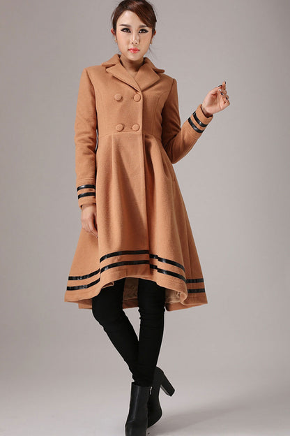 A woman wearing a brown wool long sleeve coat with notched lapels and a button-front closure. The coat has black trim detail on the cuff and hem.