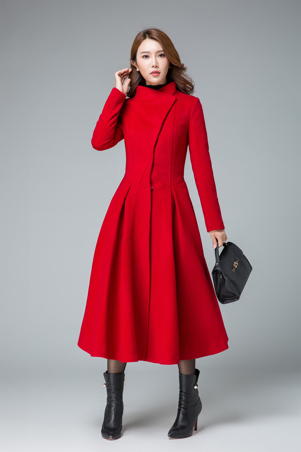 Model wearing a red asymmetrical wool coat with pleated midi skirt