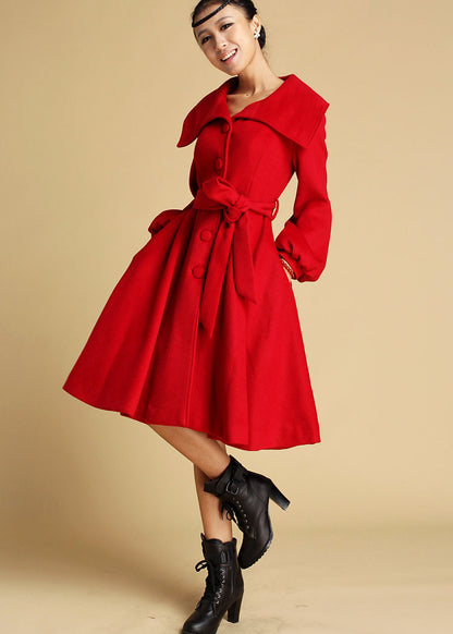 A woman modeling a red wool swing coat with large collar and front button fastening, paired with black boots.