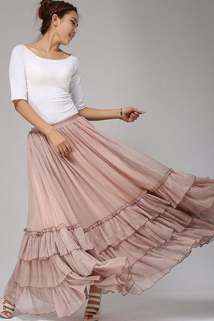 Woman wearing a white top and pink ruffled skirt on a plain background