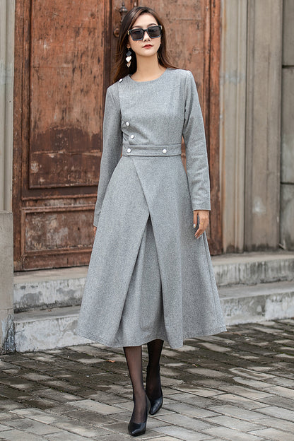 A woman wearing a grey long sleeve midi wool dress with button decoration, fully lined satin dress, standing in front of a wooden door.