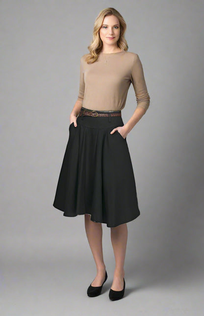 Woman wearing a beige top and black skirt on a gray background
