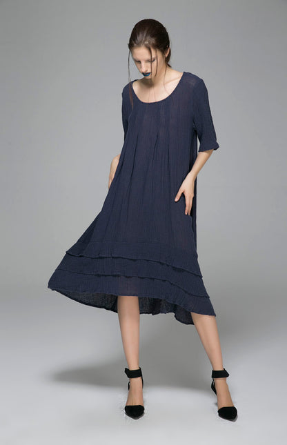 A woman modeling a navy dress with a round neck and five minute sleeves, standing on tiptoe.