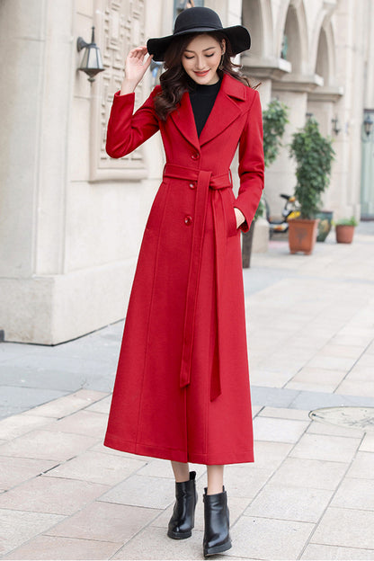 A woman wearing a red long sleeve wool coat with button closure, paired with black boots and a black hat.