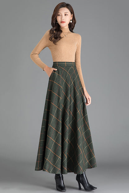 A woman wearing a beige knitted sweater and a green plaid wool skirt with a V-neckline.
